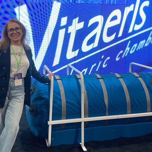Dr. D beside a Vitaeris hyperbaric chamber at a health conference